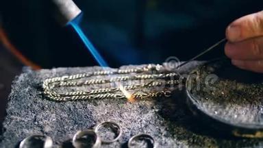 珠宝商，金匠在一个专业的珠宝车间焊接一个金属链在珠宝店。